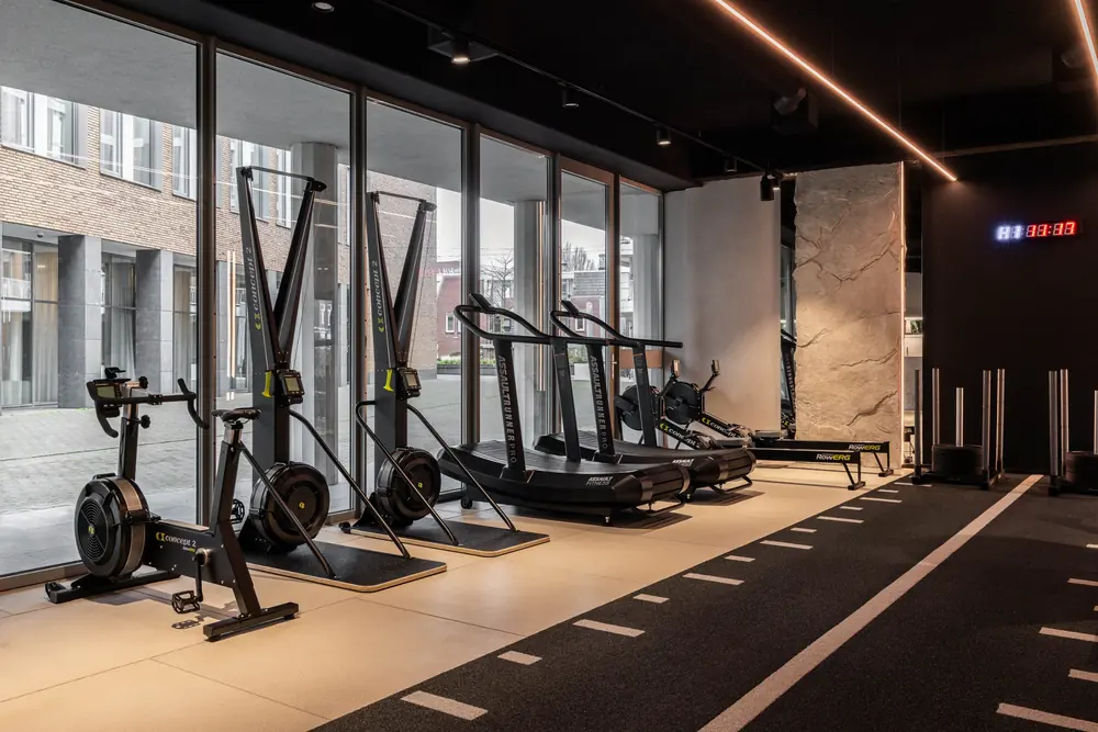 Fietsen, skiergs, loopbanden en roeiers bij de grote ramen van de studio.